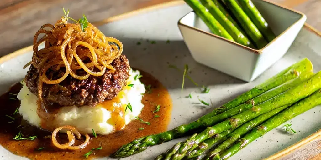 hamburger steaks topped with finely sliced caramelized onion sauce, served with a side of creamy mashed potatoes hamburger steaks topped with finely sliced caramelized onion sauce, served with a side of creamy mashed potatoes